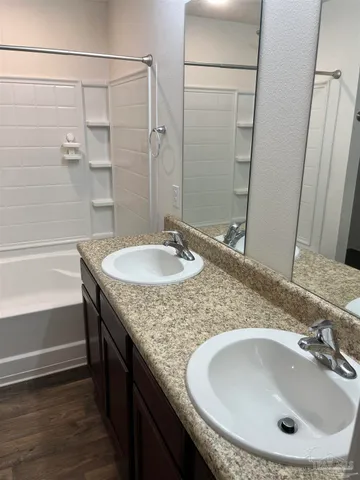 a bathroom with a granite countertop sink a mirror and shower