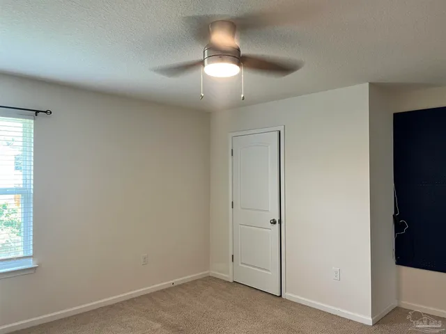 an empty room with a window and chandelier fan