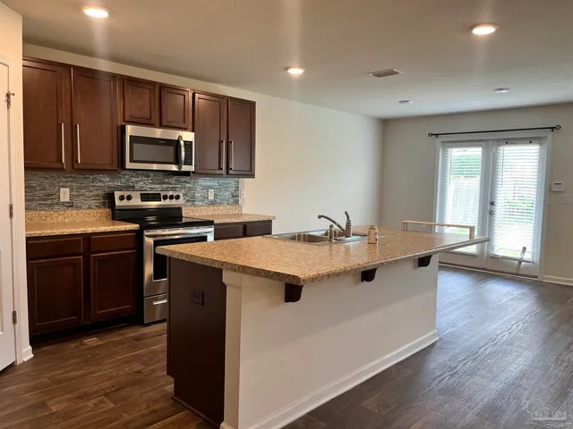 a kitchen with a sink stove top oven and refrigerator