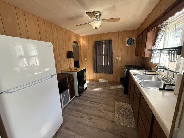 a kitchen with granite countertop a refrigerator a sink dishwasher stove and oven