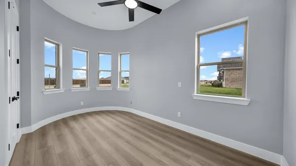 a view of an empty room with a window and wooden floor