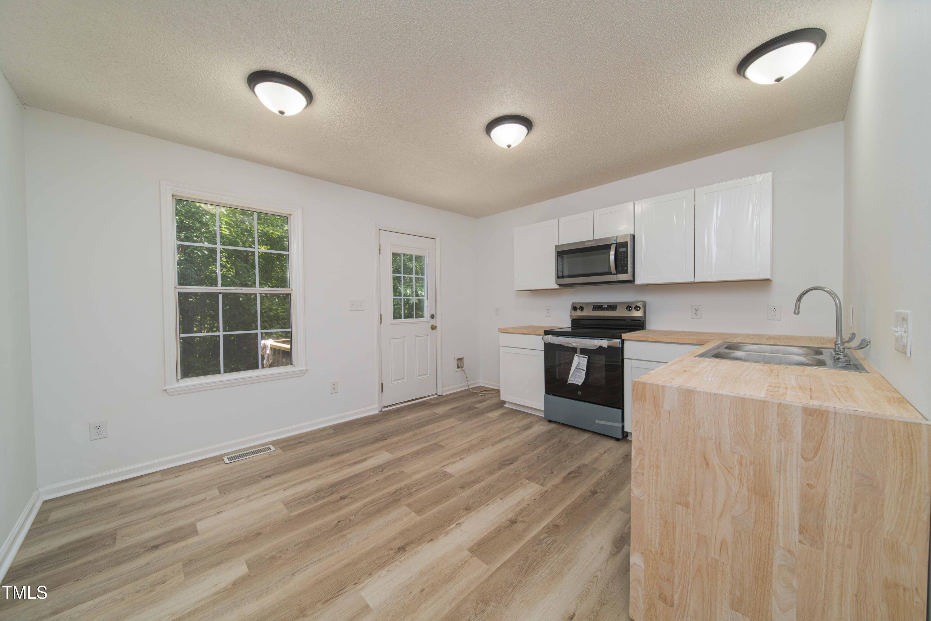 4258 Kaplan Drive Raleigh, NC 27606 - Photo 6 of 20 a kitchen with a stove a sink and a microwave