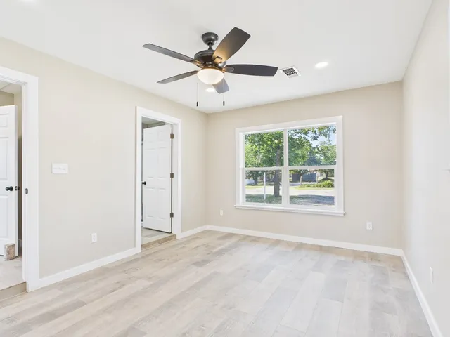 an empty room with ceiling fan and window