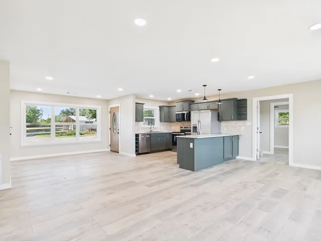 a large white kitchen with a large window and stainless steel appliances