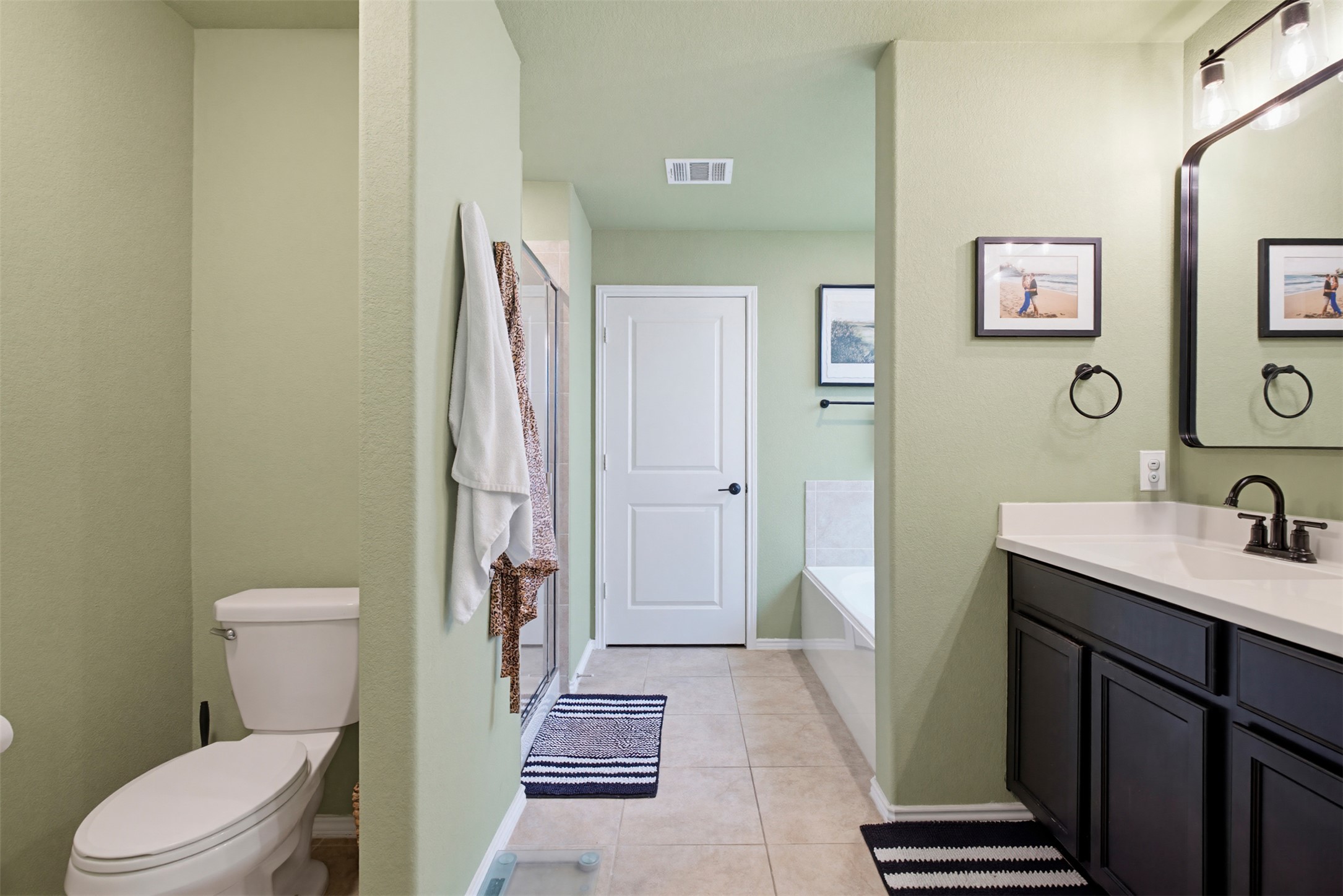5705 Southerner Way Austin, TX 78747 - Photo 10 of 22 A welcoming bathroom featuring a spacious vanity, toilet, and a large bathtub, all complemented by light green walls.