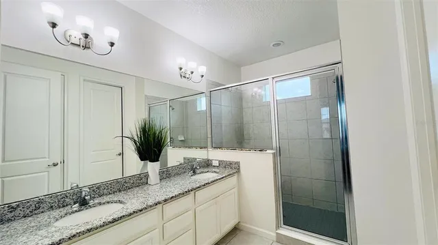 a bathroom with a granite countertop sink a mirror and a shower