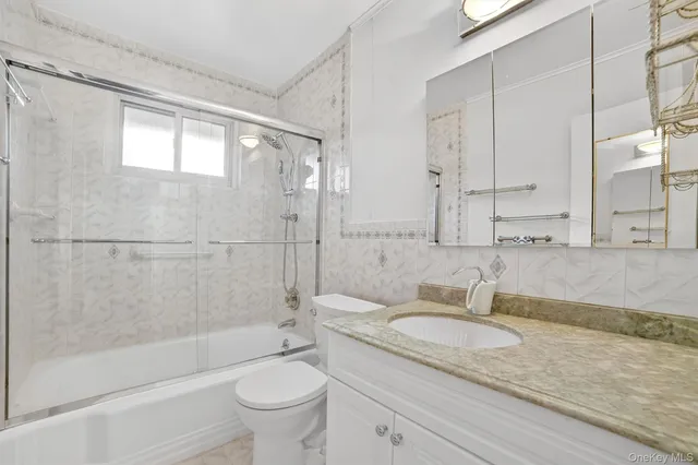a bathroom with a granite countertop sink a toilet and shower