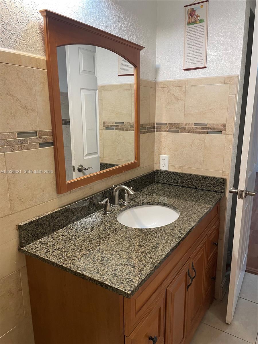 14770 Southwest 60th Street Miami, FL 33193 - Photo 12 of 16 a bathroom with a granite countertop sink and a mirror