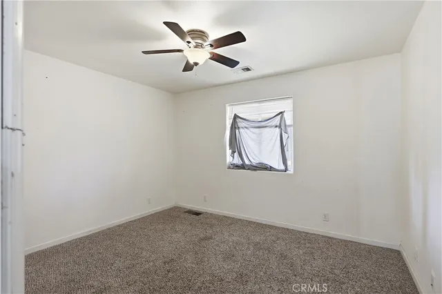 an empty room with a window and a ceiling fan