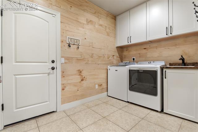 7880 Monarch Road Larkspur, CO 80118 - Photo 16 of 25 Washroom featuring wood walls, sink, light tile flooring, and washing machine and dryer