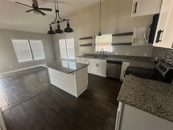a kitchen with stainless steel appliances granite countertop a sink a stove top oven a counter space and cabinets