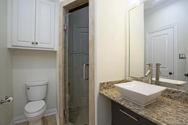 a bathroom with a granite countertop sink toilet and mirror