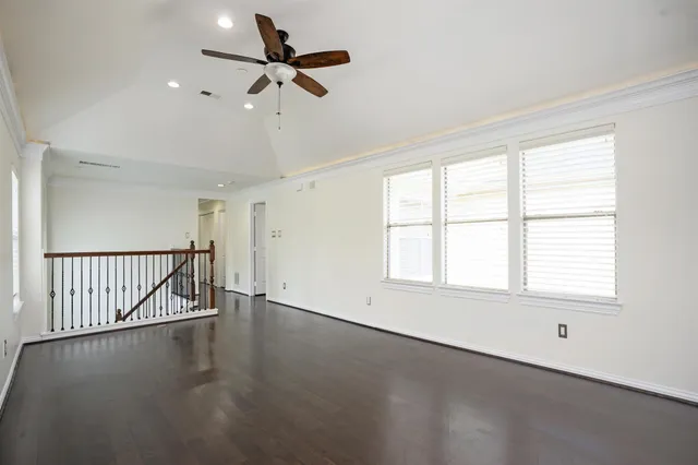 an empty room with wooden floor fan and windows