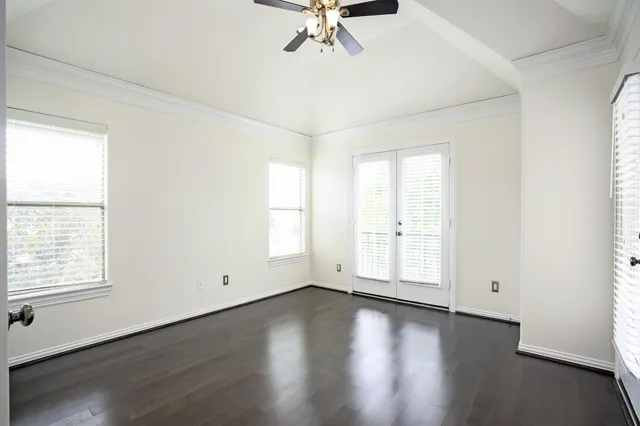 an empty room with wooden floor chandelier and windows