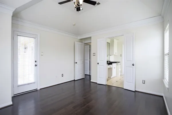 an empty room with wooden floor cabinet and windows