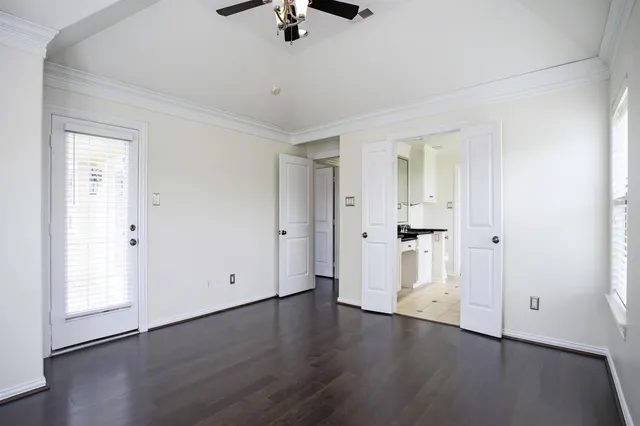 an empty room with wooden floor cabinet and windows