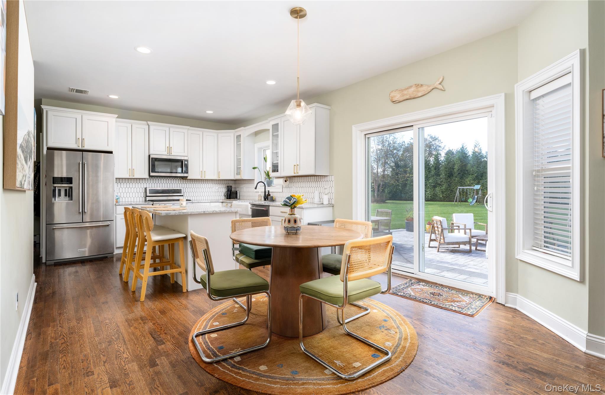 108 Calverton Court Wading River, NY 11792 - Photo 13 of 36 a dining room with stainless steel appliances kitchen island granite countertop a refrigerator a stove a sink dishwasher a dining table and chairs with wooden floor
