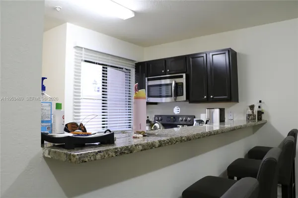 a view of a kitchen with kitchen island a sink a window and a potted plant