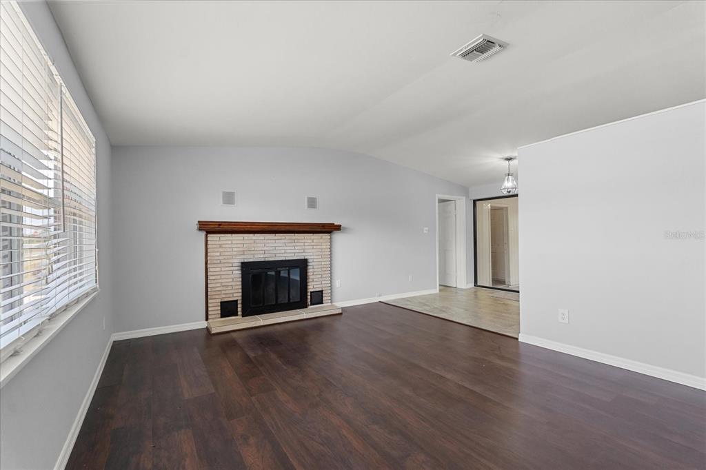 4070 McNeil Road Apopka, FL 32703 - Photo 5 of 28 an empty room with wooden floor fireplace and windows
