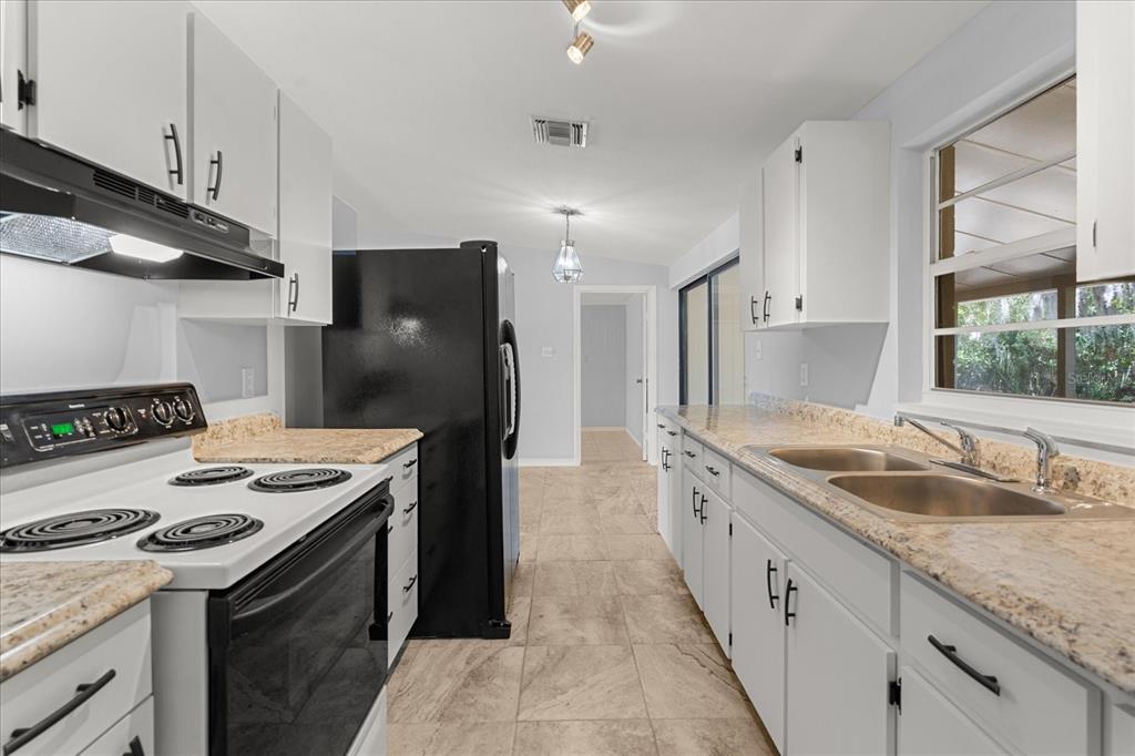 4070 McNeil Road Apopka, FL 32703 - Photo 7 of 28 a kitchen with granite countertop a sink stove and refrigerator