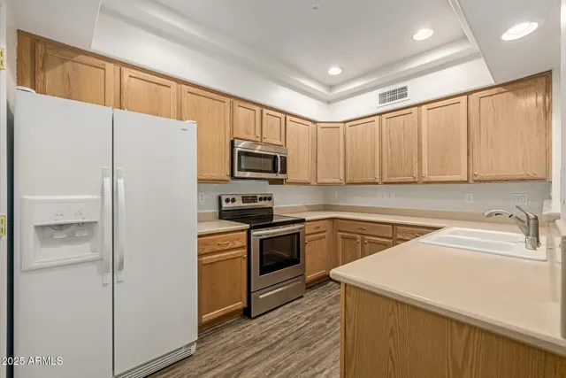 a kitchen with a refrigerator a stove top oven a sink and cabinets