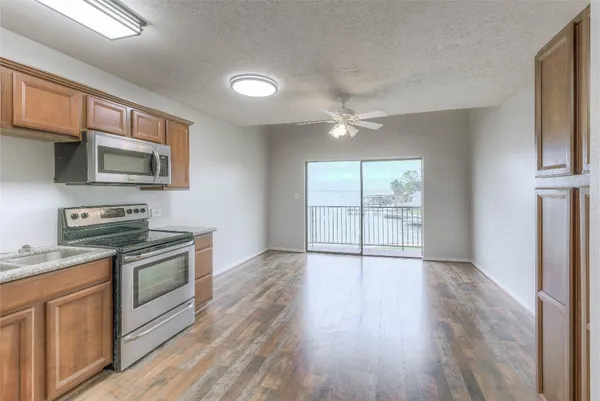 a kitchen with stainless steel appliances granite countertop a stove top oven a sink dishwasher a microwave oven and a refrigerator with wooden floor