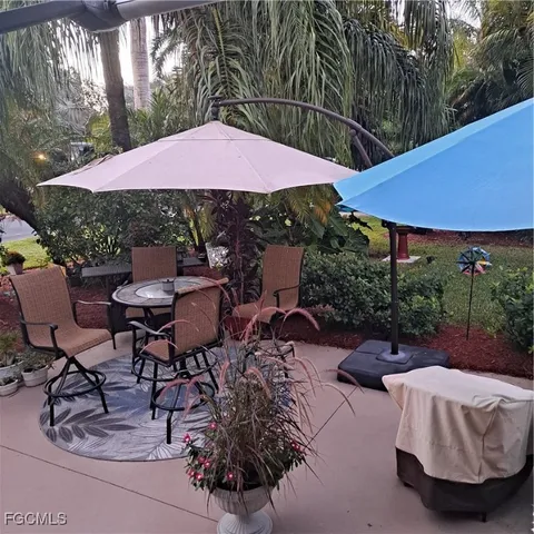 a view of patio with chairs and table under an umbrella