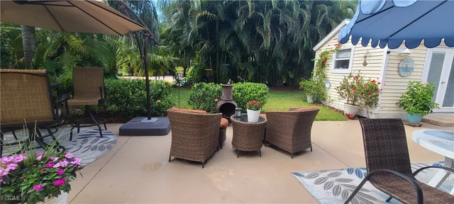 a view of a patio with table and chairs potted plants and palm trees