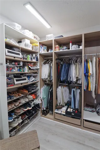 a view of walk in closet with clothes and shoes