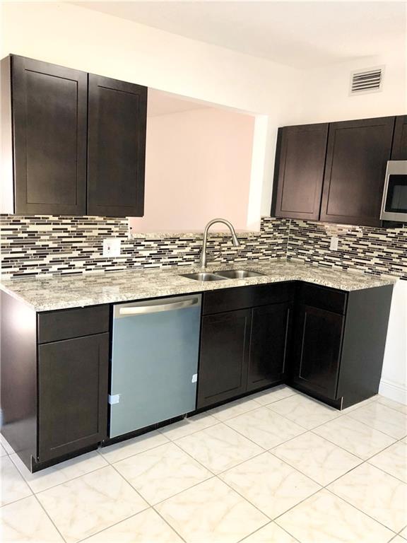 1625 Queensway Road Orlando, FL 32808 - Photo 22 of 32 Newly renovated kitchen with all new appliances. Gorgeous back splash with dishwasher and microwave. Matching stove and refrigerator are currently installed.