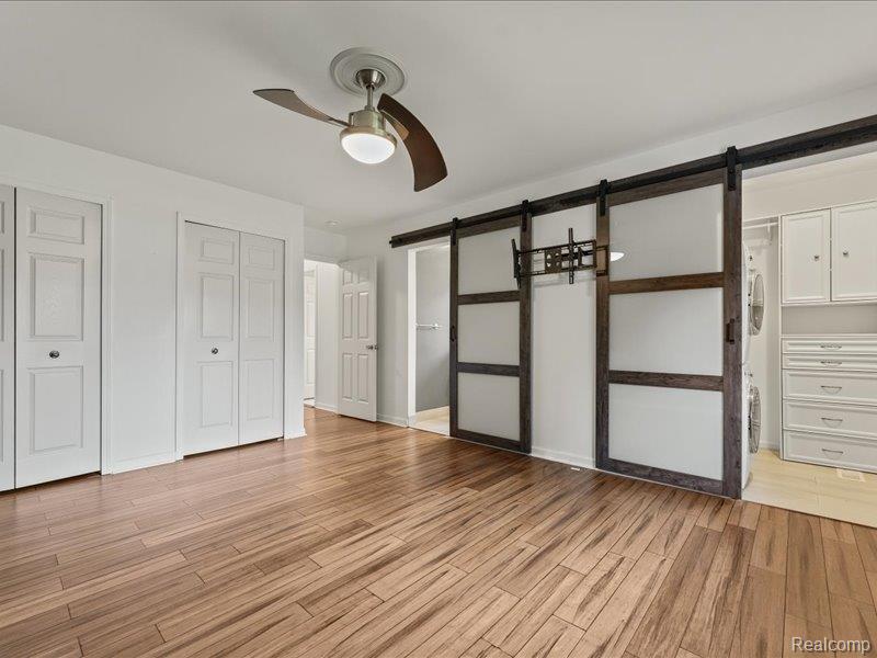 29213 Rachid Lane New Baltimore, MI 48047 - Photo 13 of 26 Unfurnished bedroom with a barn door, multiple closets, ensuite bath, and light wood-type flooring
