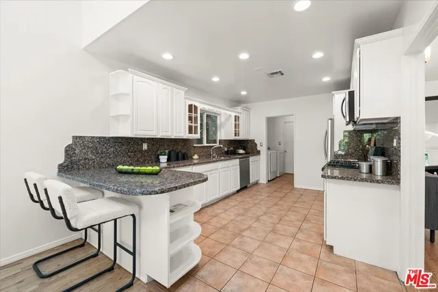 a kitchen with stainless steel appliances kitchen island granite countertop a sink and cabinets