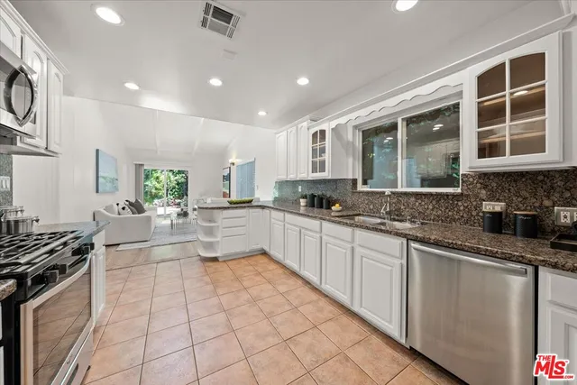 a large kitchen with stainless steel appliances granite countertop a large stove top oven a sink a dining table and chairs