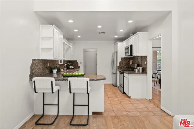 a kitchen with stainless steel appliances kitchen island granite countertop a refrigerator and microwave