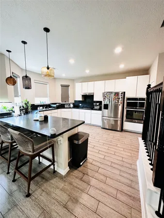 a kitchen with stainless steel appliances kitchen island granite countertop a table chairs and a refrigerator