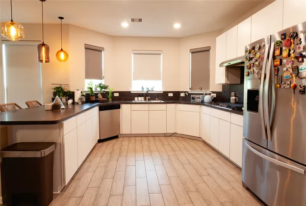 a large kitchen with stainless steel appliances granite countertop a refrigerator a sink dishwasher a stove with wooden floor and cabinets