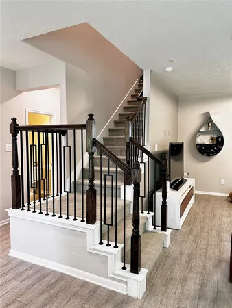 a view of staircase with lots of frames on wall and wooden floor