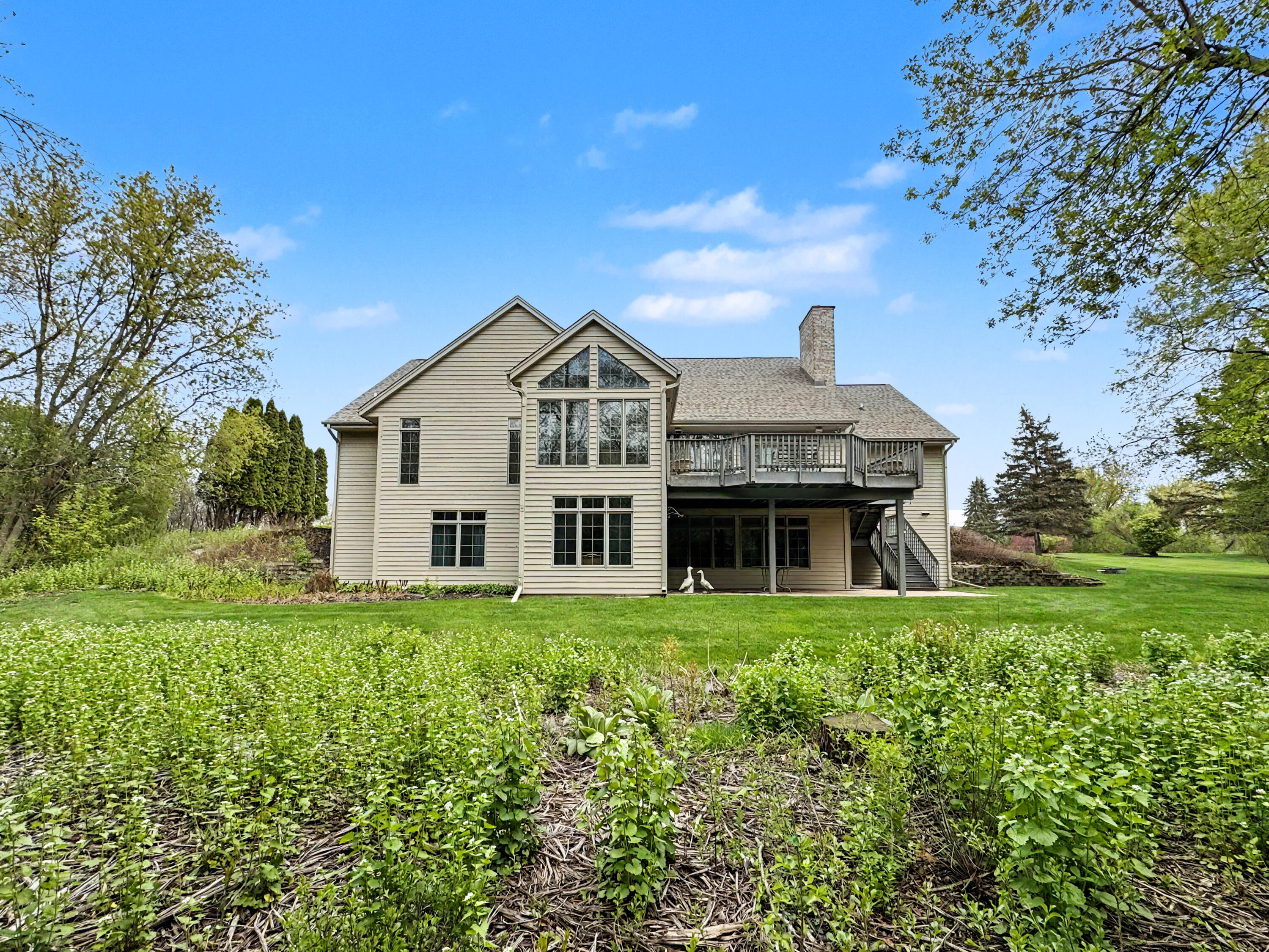 W291-s5245 Ridgefield Road Waukesha, WI 53189 - Photo 4 of 44 Walls of windows, a composite deck, and a covered patio overlook the private 3-acre setting, creating exceptional indoor-outdoor living.