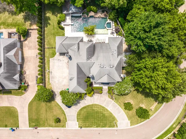 an aerial view of a house with swimming pool and large trees