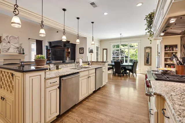 a kitchen with stainless steel appliances granite countertop a sink a stove and a wooden floors