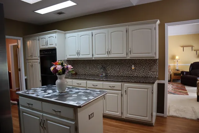 a kitchen with granite countertop a stove a sink dishwasher and white cabinets