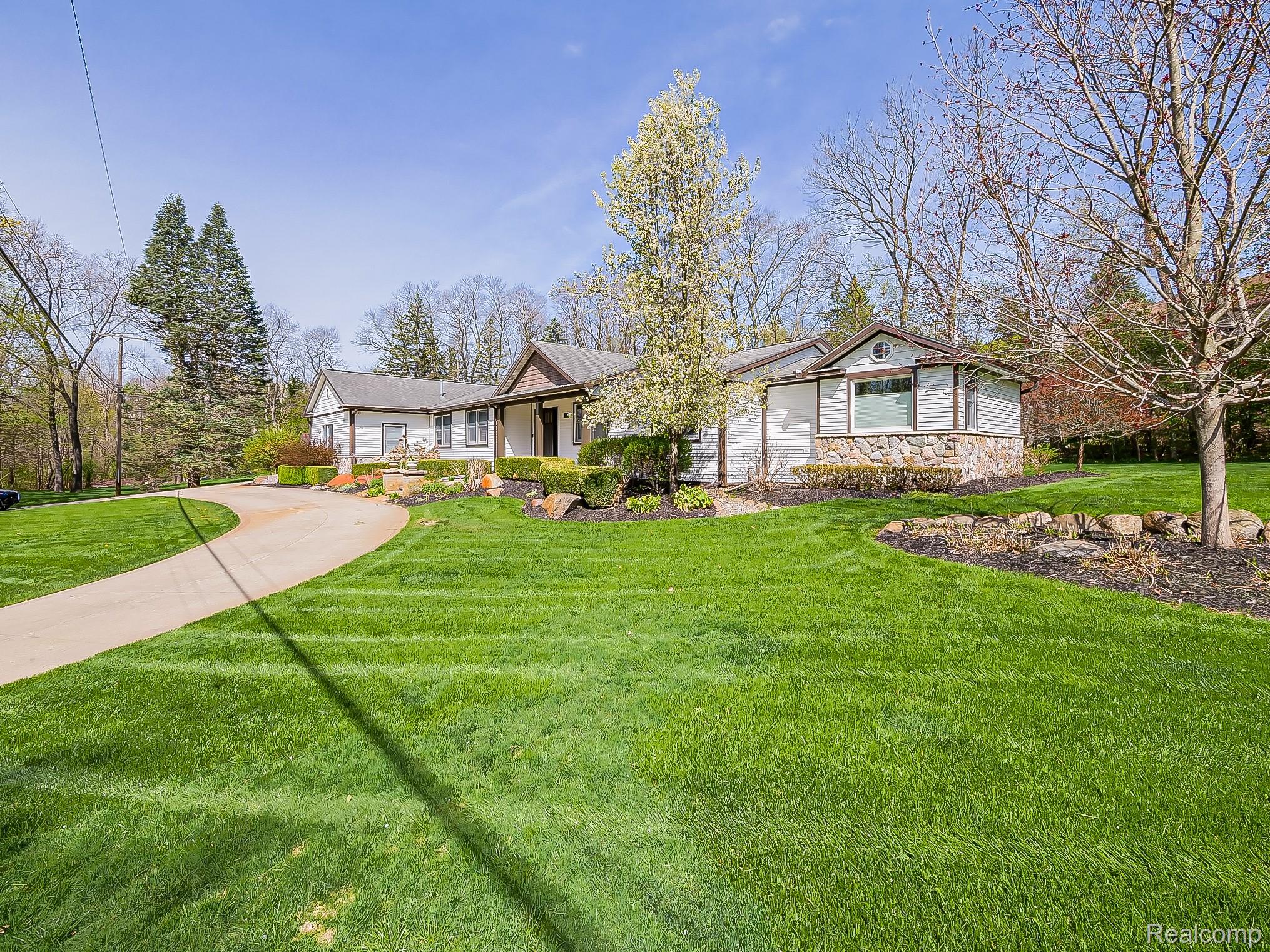 3720 East Clarkston Road Oakland, MI 48363 - Photo 52 of 60 View of front facade with stone siding, a front lawn, covered porch, and concrete driveway