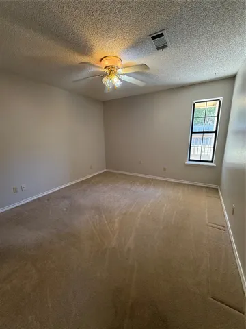 an empty room with windows and ceiling fan