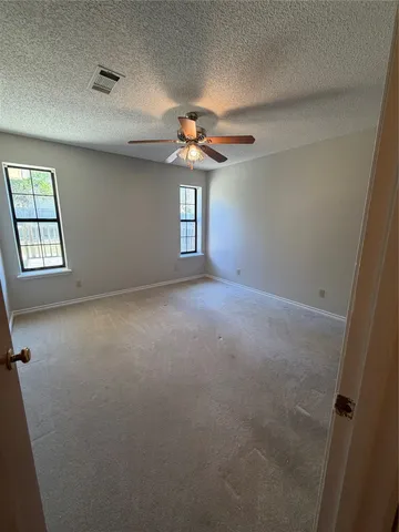 an empty room with windows and fan