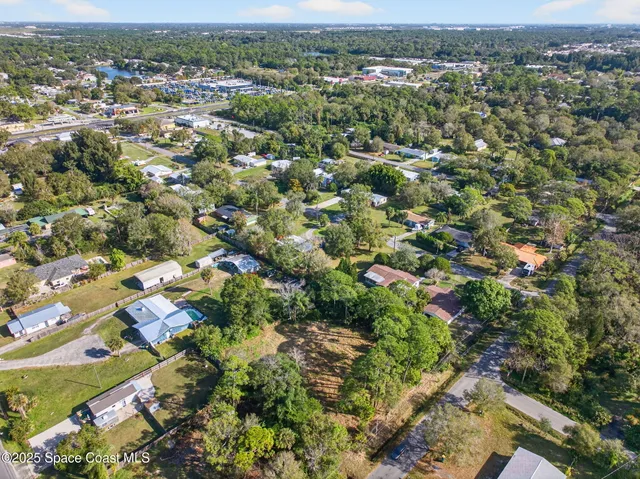an aerial view of residential houses with outdoor space and trees