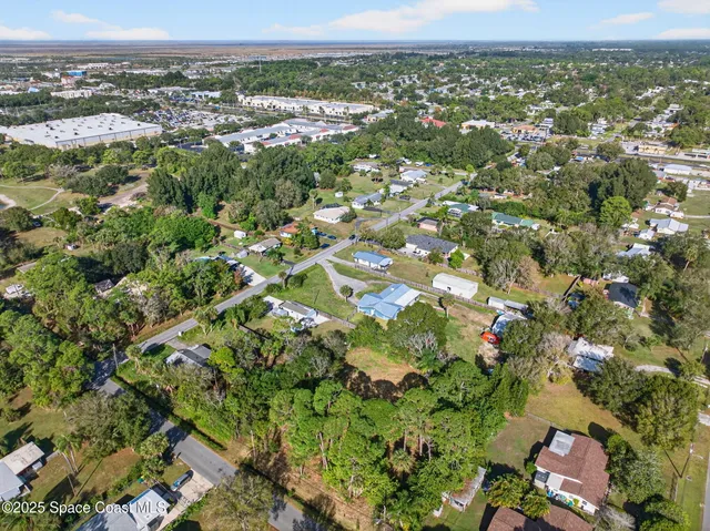 an aerial view of residential houses with outdoor space and trees