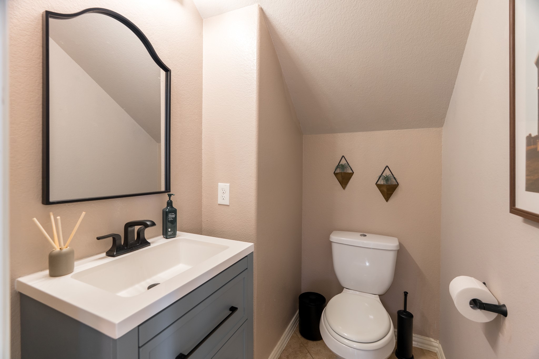 79 West Jagged Ridge Circle Spring, TX 77389 - Photo 28 of 50 This stylish powder room offers a soft, warm color palette, a sleek pedestal-style vanity, and modern matte black fixtures. Conveniently located on the main floor, it's a thoughtfully designed space that's both functional and welcoming for guests.