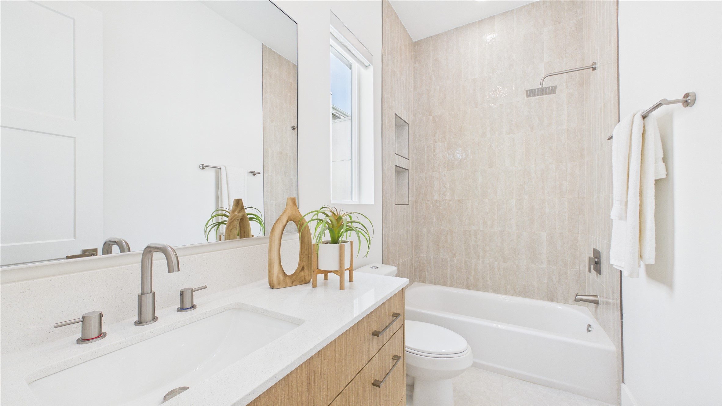 602 Skyland Terrace Way Houston, TX 77009 - Photo 25 of 40 This modern bathroom features a sleek design with a dual sink vanity, contemporary fixtures, a large mirror, and a bathtub with a rainfall showerhead. Neutral tones and natural light enhance the clean, spacious feel.