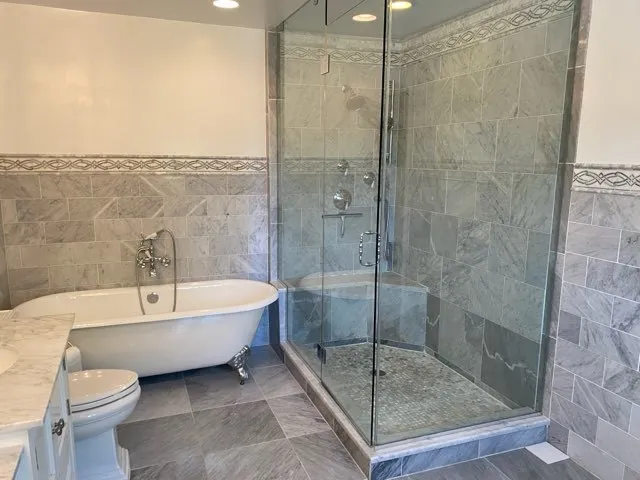 a bathroom with a white bath tub a toilet and a shower