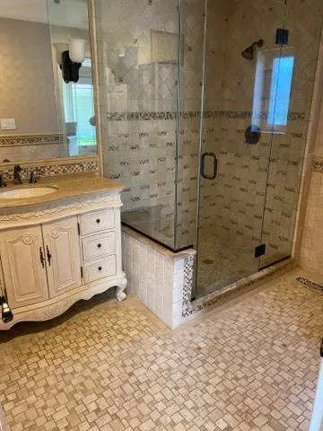 a bathroom with a granite countertop sink a mirror and shower
